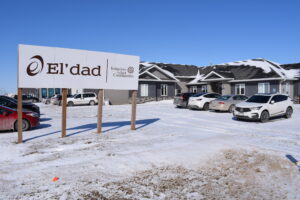 El'dad office in Mitchell. Sign with El'dad and Initiatives for Just Communities logo in front of low blue building. Snow on ground